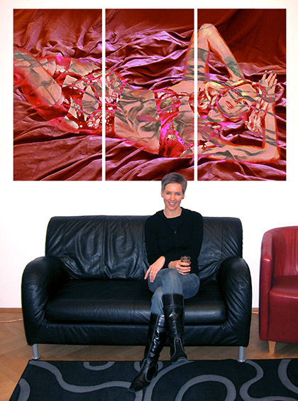 Nicole Röther sitzend auf einer schwarzen Couch mit Ihrem Bild Pink Lady, welches über der Couch hängt